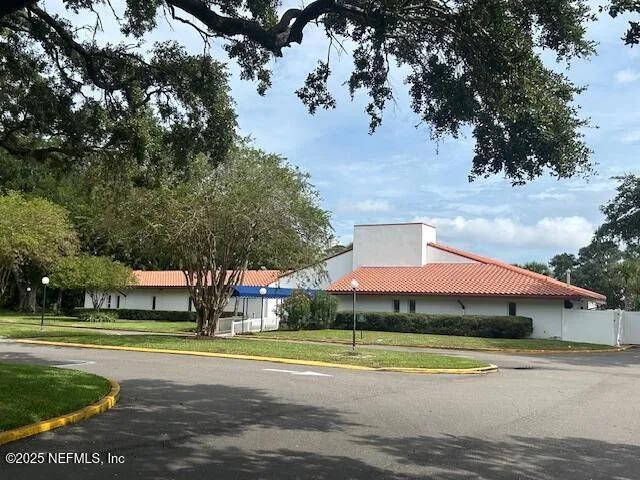 a view of a white house with a big yard plants and large trees