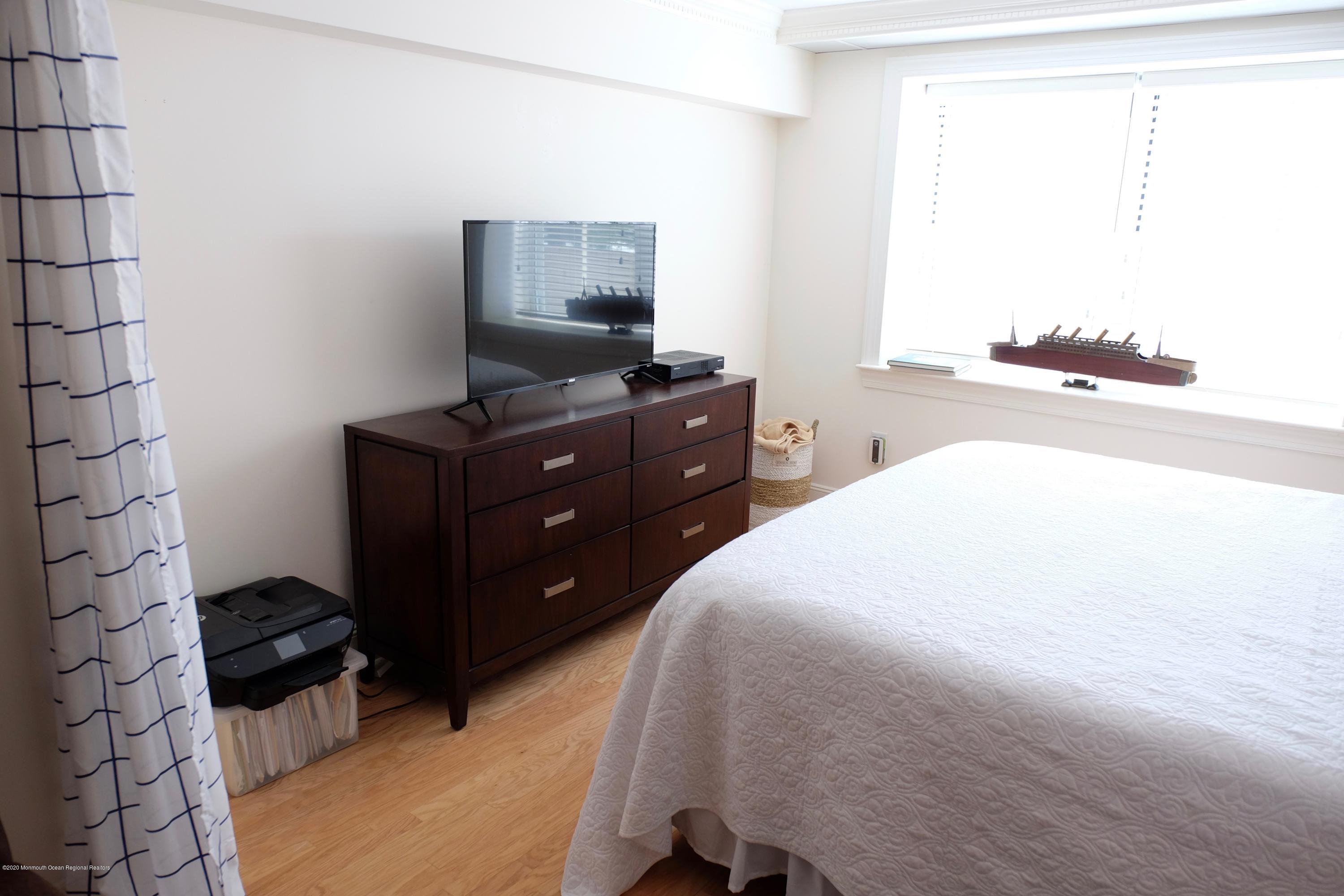 700 Ocean Avenue, Unit G1 Spring Lake, NJ 07762 - Photo 13 of 42 a bedroom with a bed and a flat tv screen on the dresser
