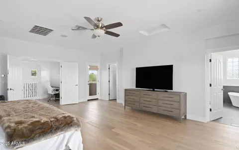 a spacious bedroom with a bed and a flat screen tv