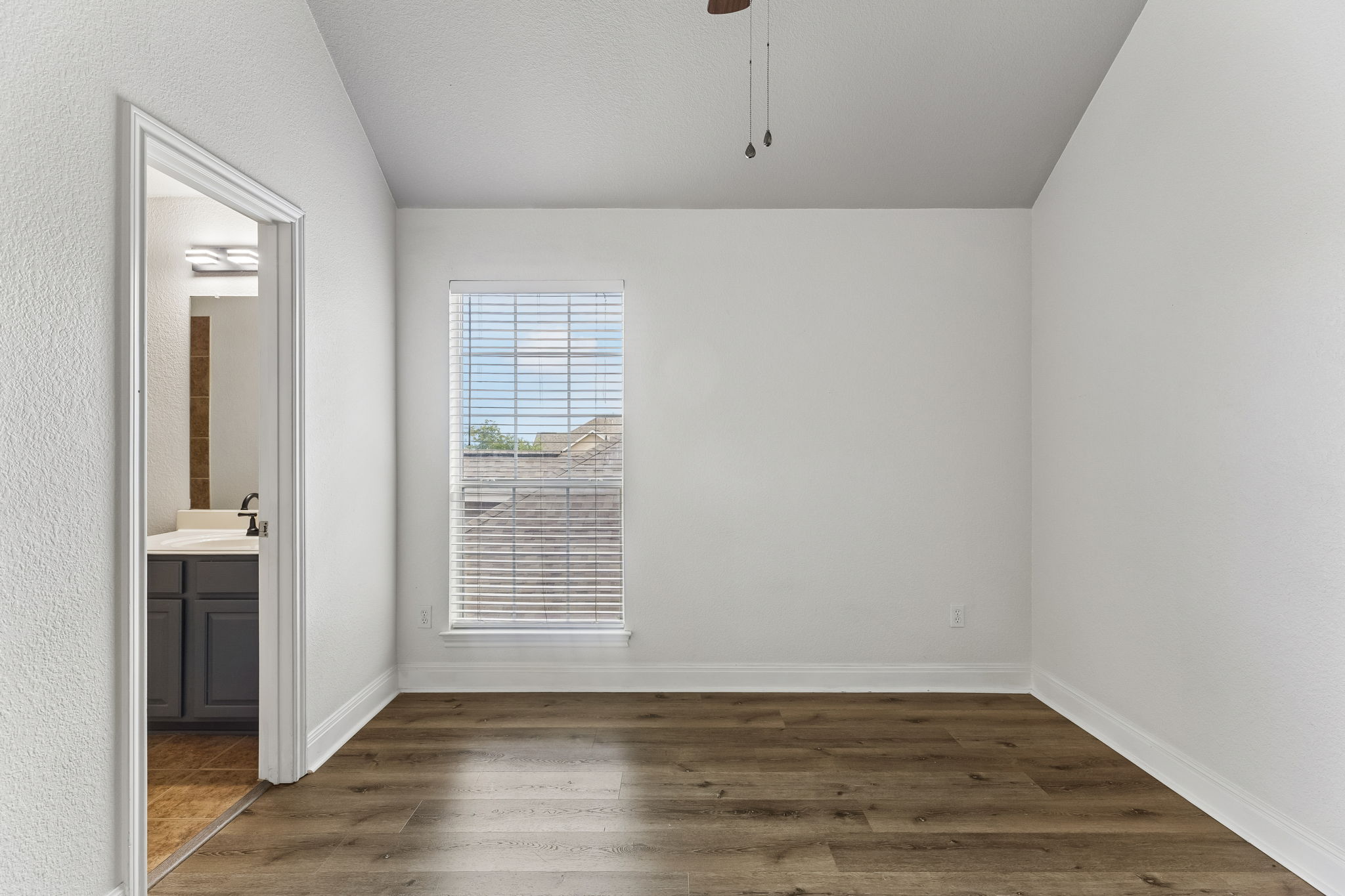 114 Aria Ridge, Unit 802 Lakeway, TX 78738 - Photo 16 of 37 Wood flooring and a window with blinds provide a neutral backdrop for any design vision.