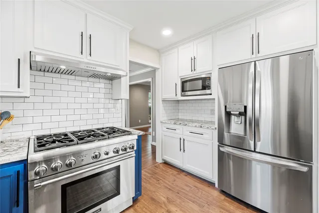 a kitchen with cabinets stainless steel appliances and wooden floor