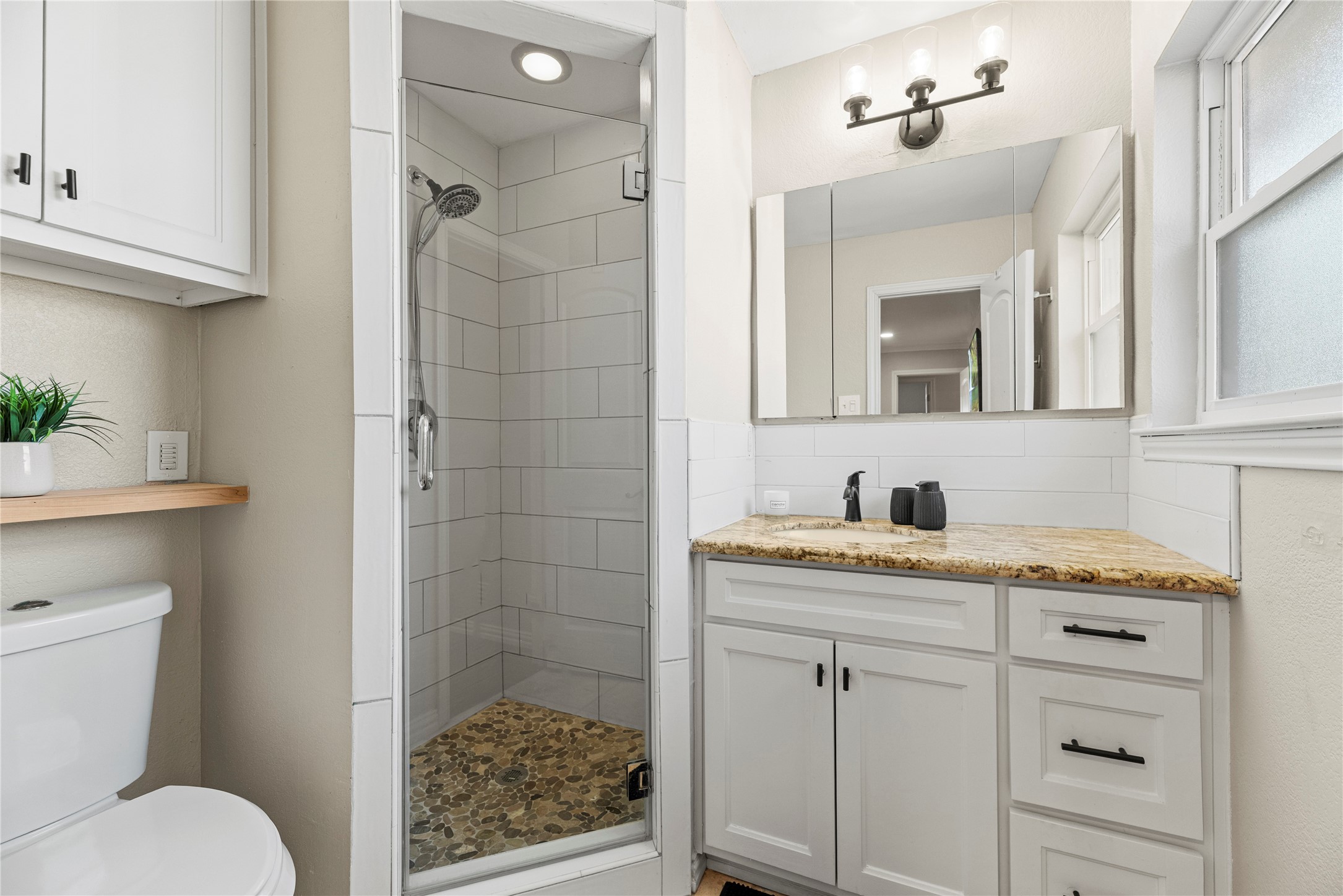 6031 McKnight Street Houston, TX 77035 - Photo 23 of 37 a bathroom with a granite countertop sink a mirror a vanity and a shower