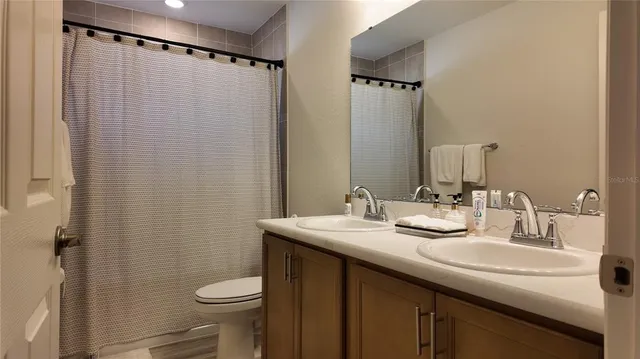 a bathroom with a sink a toilet a mirror and shower curtain