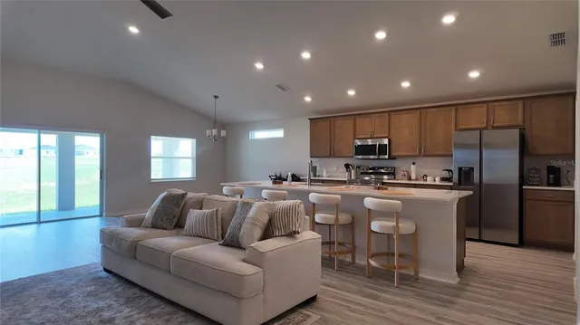 a kitchen with stainless steel appliances granite countertop a refrigerator a sink dishwasher a stove and white cabinets with wooden floor