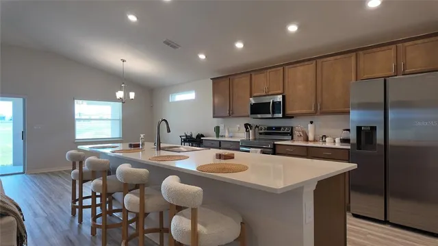 a kitchen with sink a refrigerator and chairs