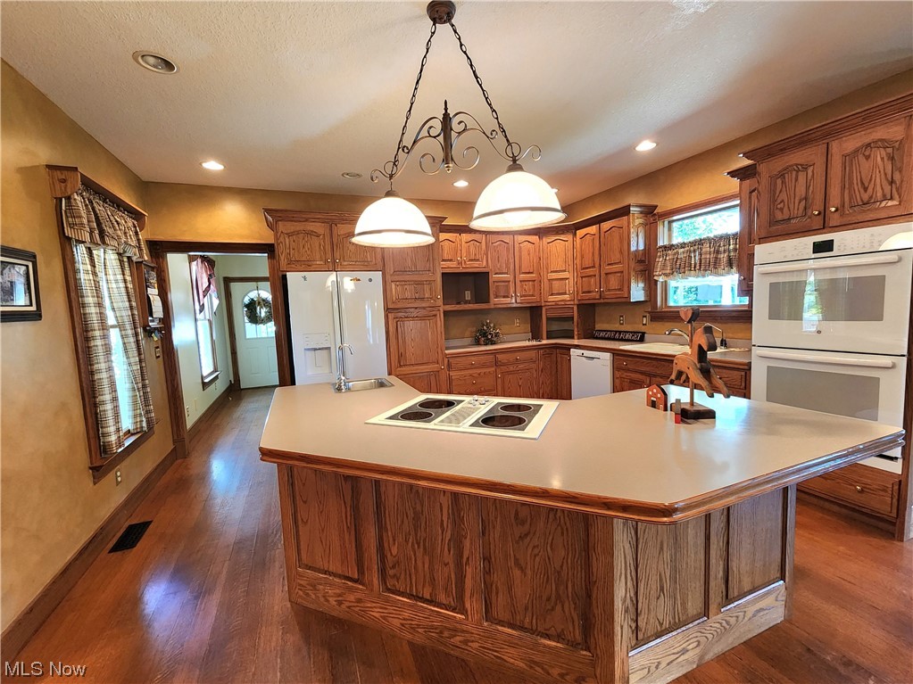 14132 South State Road Dresden, OH 43821 - Photo 32 of 35 Kitchen featuring pendant lighting, brown cabinets, wood-type flooring, light countertops, and white appliances