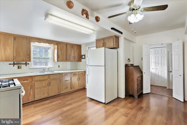 a kitchen with stainless steel appliances granite countertop a refrigerator a sink dishwasher a stove and a dining table with wooden floor