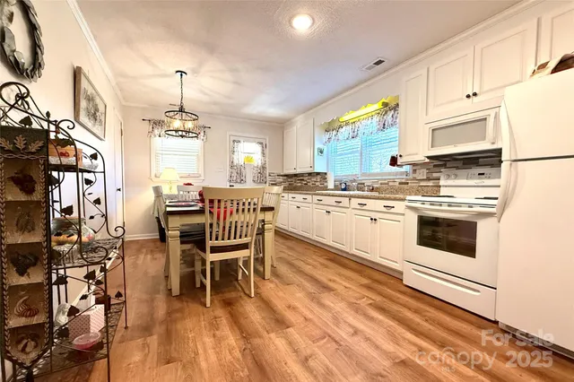 a kitchen with a table chairs a sink dishwasher and cabinets with wooden floor