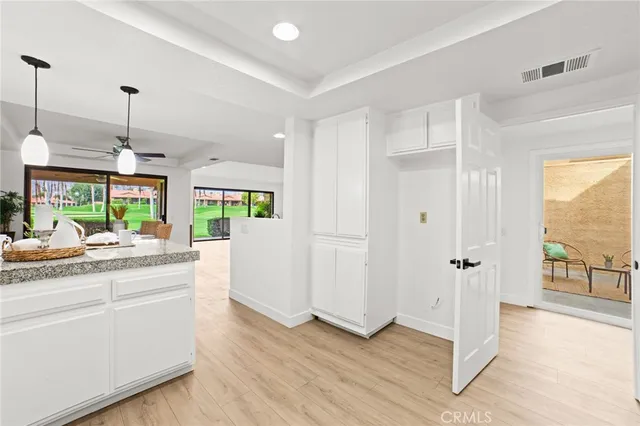 a kitchen with stainless steel appliances granite countertop a refrigerator a sink dishwasher and white cabinets with wooden floor