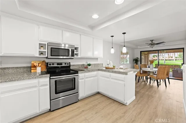 a kitchen with white cabinets stainless steel appliances and wooden floor