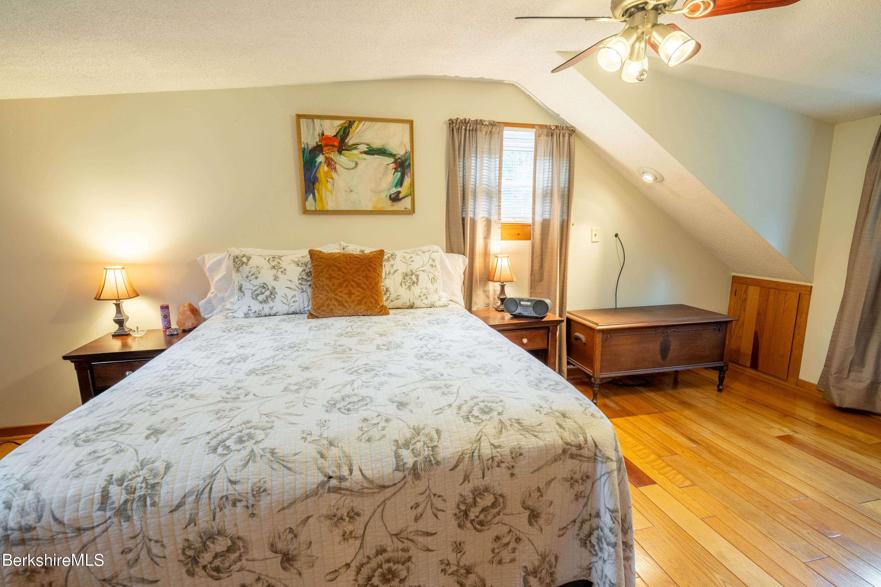 135 Ed Jones Road Otis, MA 01253 - Photo 36 of 45 a spacious bedroom with a bed and a chandelier