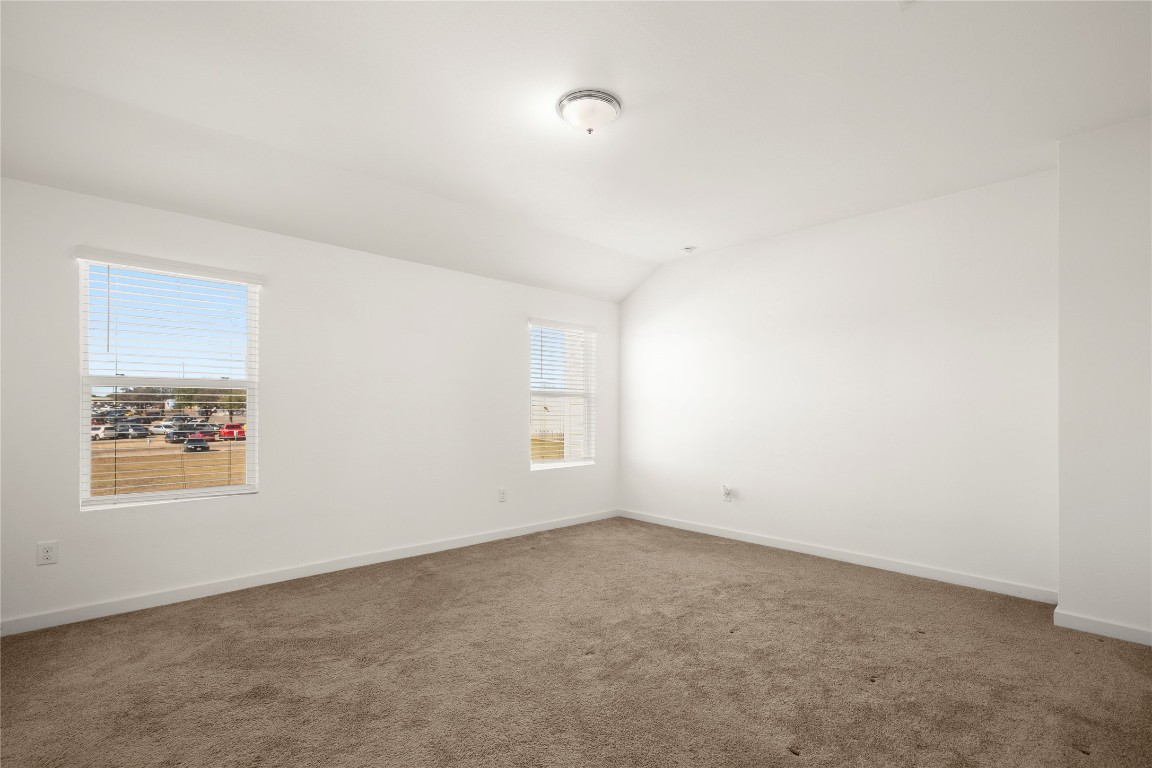 15004 Ryman Road Austin, TX 78660 - Photo 18 of 23 Carpeted spare room with vaulted ceiling and baseboards