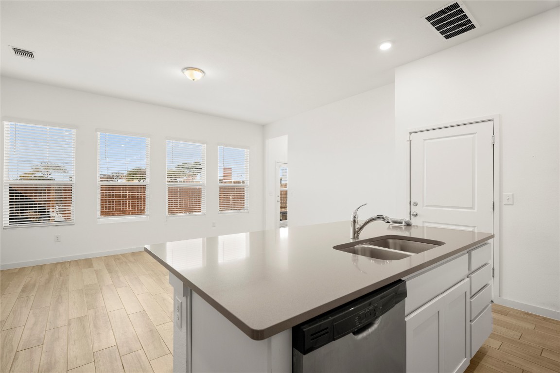 15004 Ryman Road Austin, TX 78660 - Photo 5 of 23 Kitchen with dishwasher, white cabinets, light wood finished floors, an island with sink, and recessed lighting