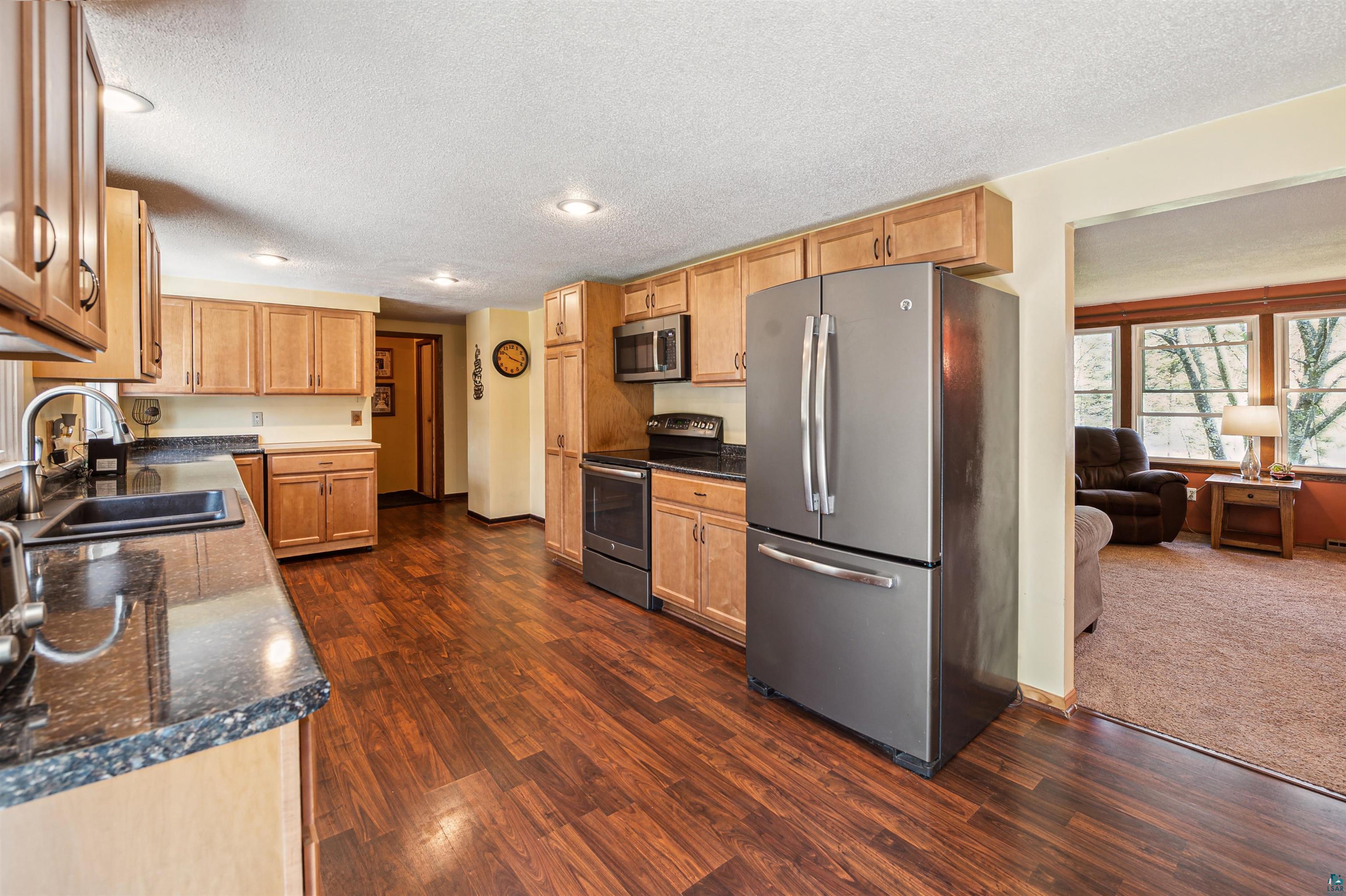 28 North Cloquet Road East Esko, MN 55733 - Photo 4 of 26 Kitchen featuring stainless steel appliances, dark hardwood / wood-style flooring, a textured ceiling, and sink