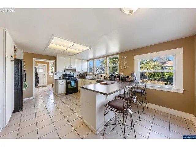 a open kitchen with stainless steel appliances granite countertop a refrigerator dining table and chairs