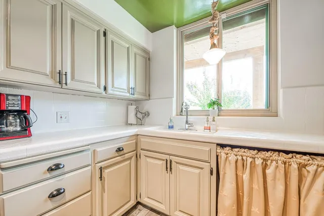a kitchen with white cabinets and a window