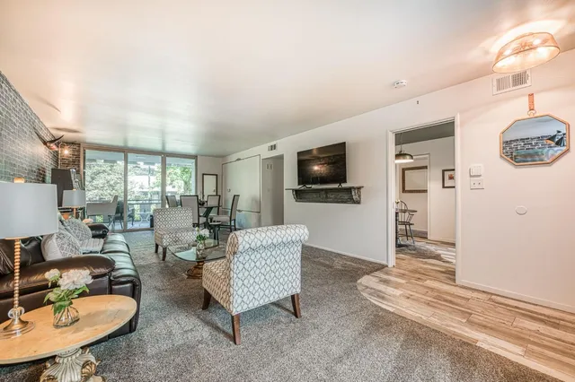 a living room with furniture a flat screen tv and kitchen view
