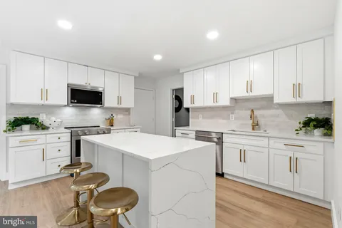 a large white kitchen with granite countertop a large window