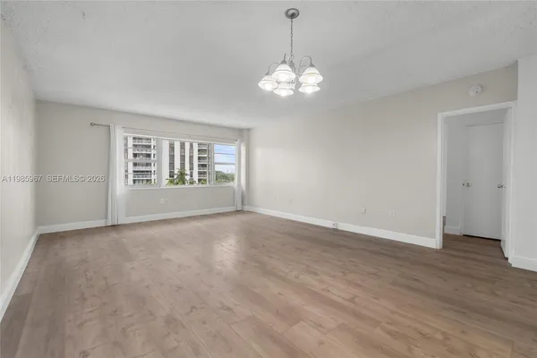 a view of an empty room with a window and wooden floor