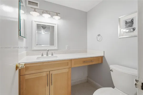 a bathroom with a toilet sink vanity and mirror