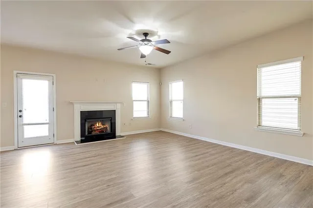 an empty room with windows fireplace and wooden floor