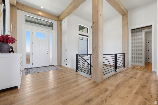 4331 West 475 South West Point, UT 84015 - Photo 22 of 46 Wood-finish flooring throughout, exposed wood beams, white paneled entry door with sidelights and transom window, and a black metal railing