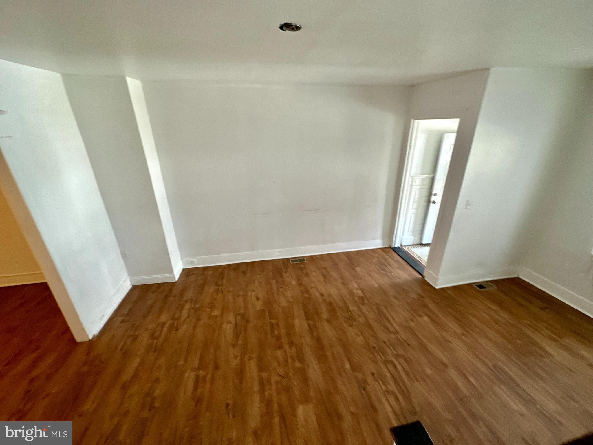 an empty room with wooden floor and entrance