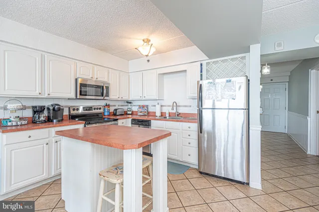 a kitchen with stainless steel appliances granite countertop a refrigerator a stove a sink a microwave and white cabinets