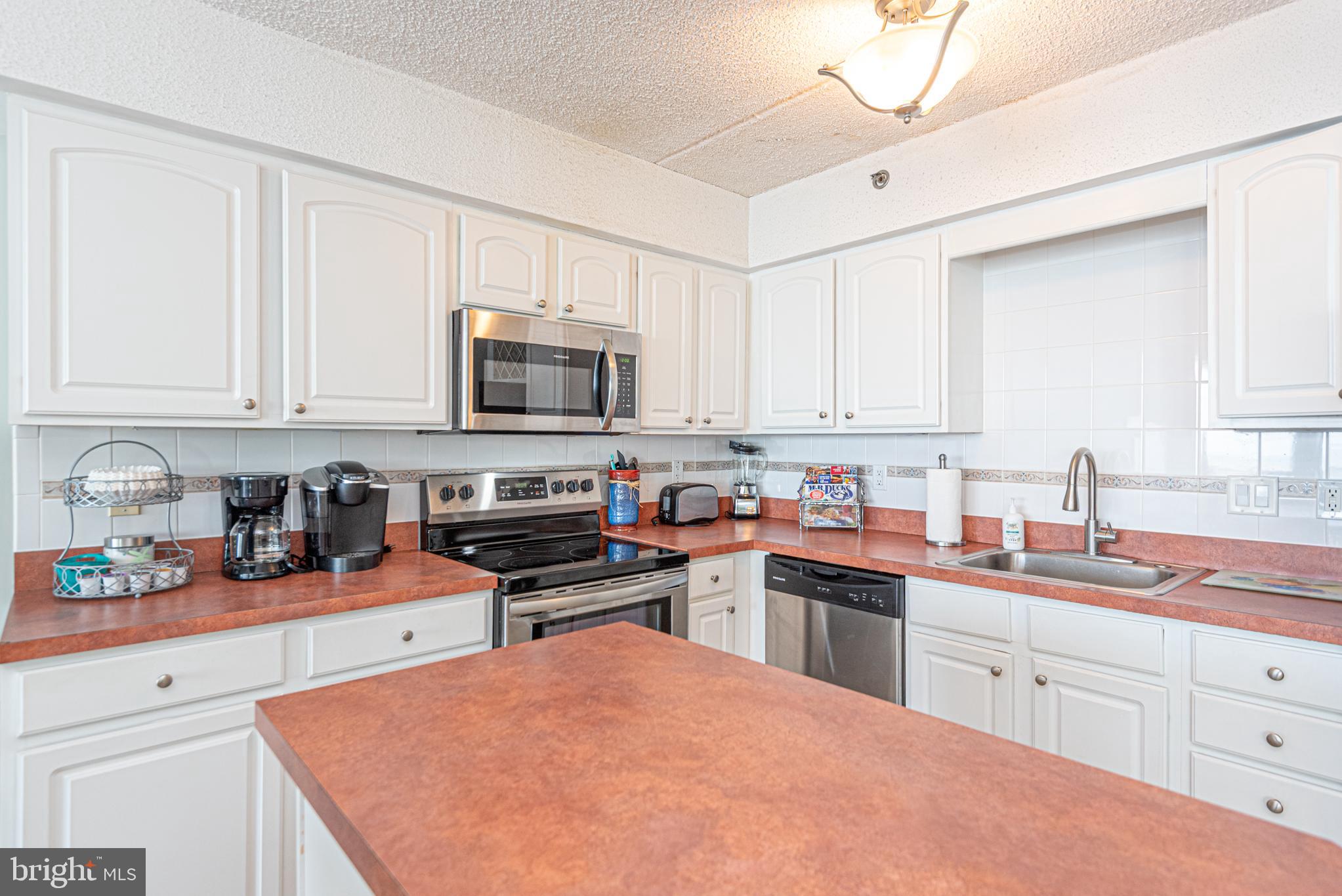 11700 Coastal Highway, Unit 1109 Ocean City, MD 21842 - Photo 27 of 50 a kitchen with stainless steel appliances a sink dishwasher stove microwave and cabinets