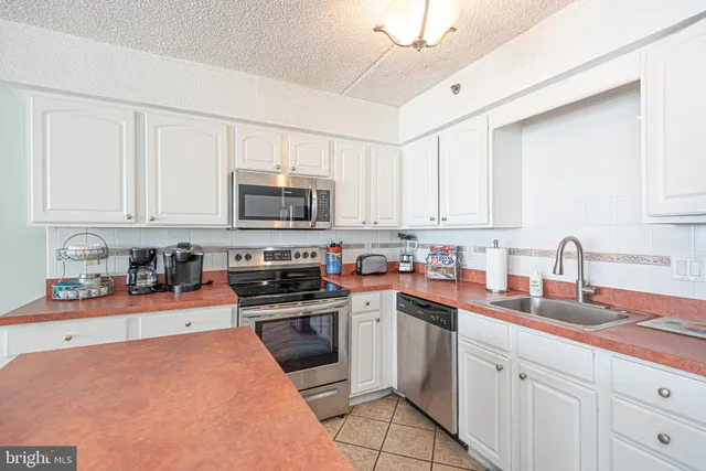 a kitchen with stainless steel appliances granite countertop a sink dishwasher stove top oven and cabinets with wooden floor