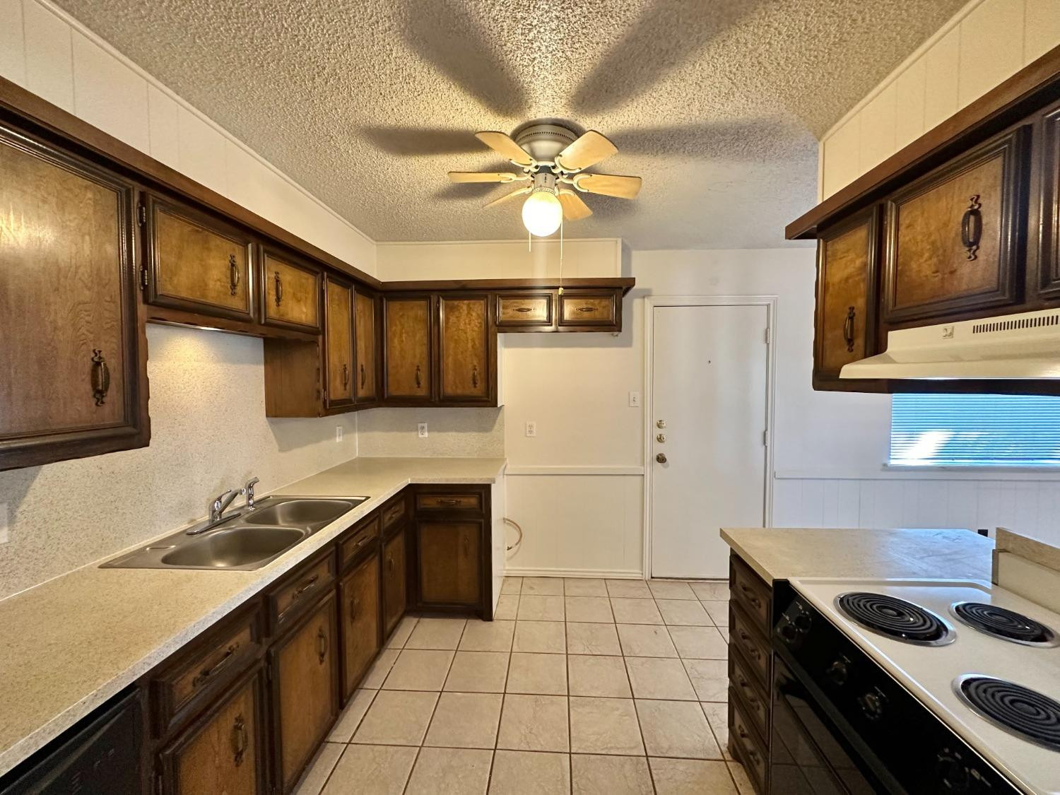 7805 Memphis Avenue, Unit B Lubbock, TX 79423 - Photo 4 of 13 a kitchen with a stove a sink and a refrigerator