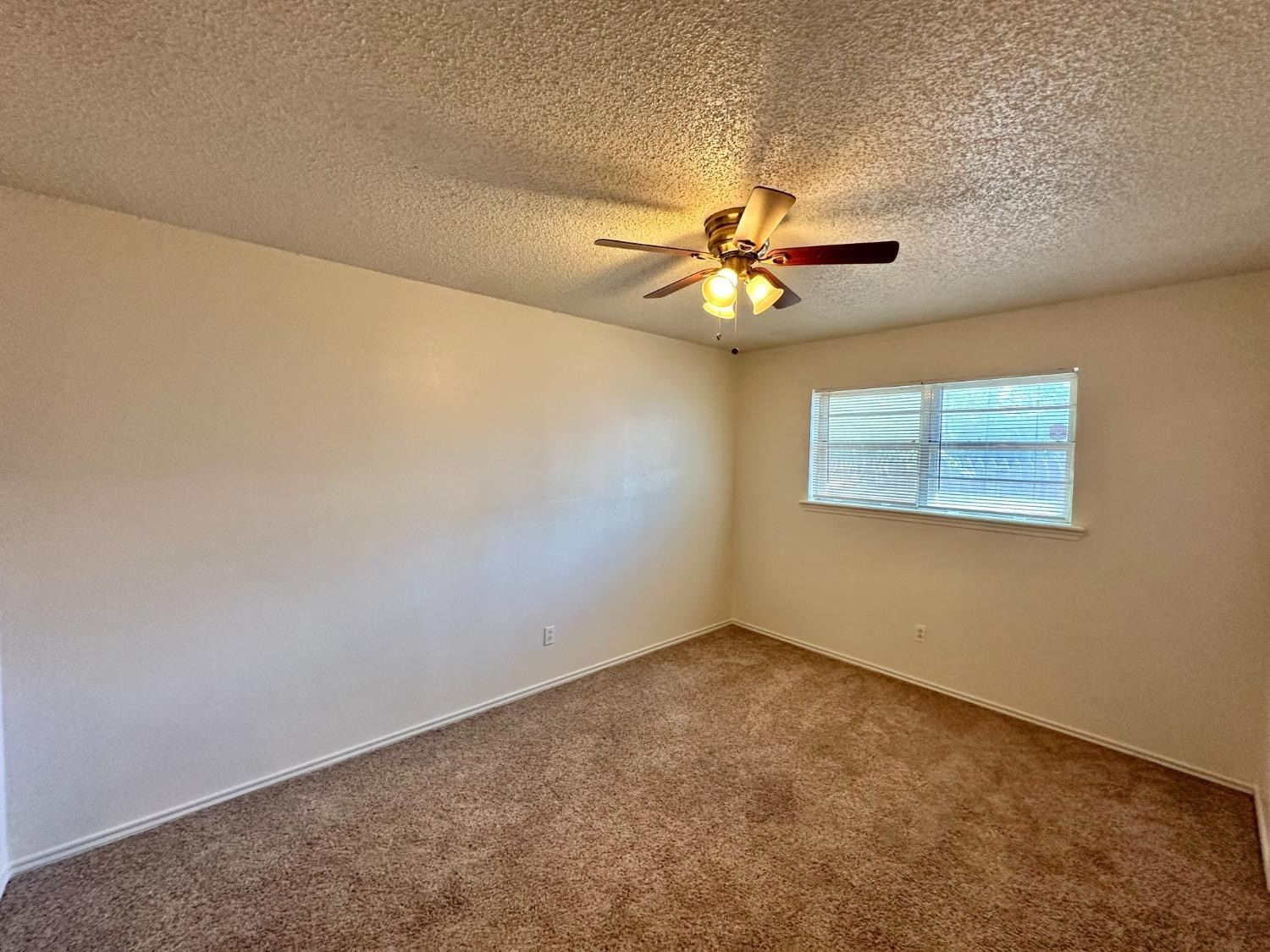 7805 Memphis Avenue, Unit B Lubbock, TX 79423 - Photo 6 of 13 an empty room with a window and a ceiling fan