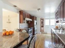 12 Ross Avenue Melville, NY 11747 - Photo 3 of 15 Kitchen featuring a breakfast bar area, light wood-style flooring, appliances with stainless steel finishes, and dark stone countertops