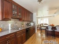 12 Ross Avenue Melville, NY 11747 - Photo 4 of 15 Kitchen featuring decorative backsplash, light wood-type flooring, light countertops, hanging light fixtures, and glass insert cabinets