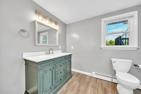 a bathroom with a granite countertop toilet a sink and a mirror
