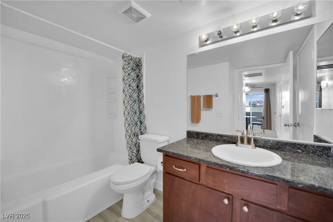 2300 East Silverado Ranch Boulevard, Unit 1189 Las Vegas, NV 89123 - Photo 24 of 27 Bathroom featuring shower / bath combination with curtain, vanity, and light wood-style floors
