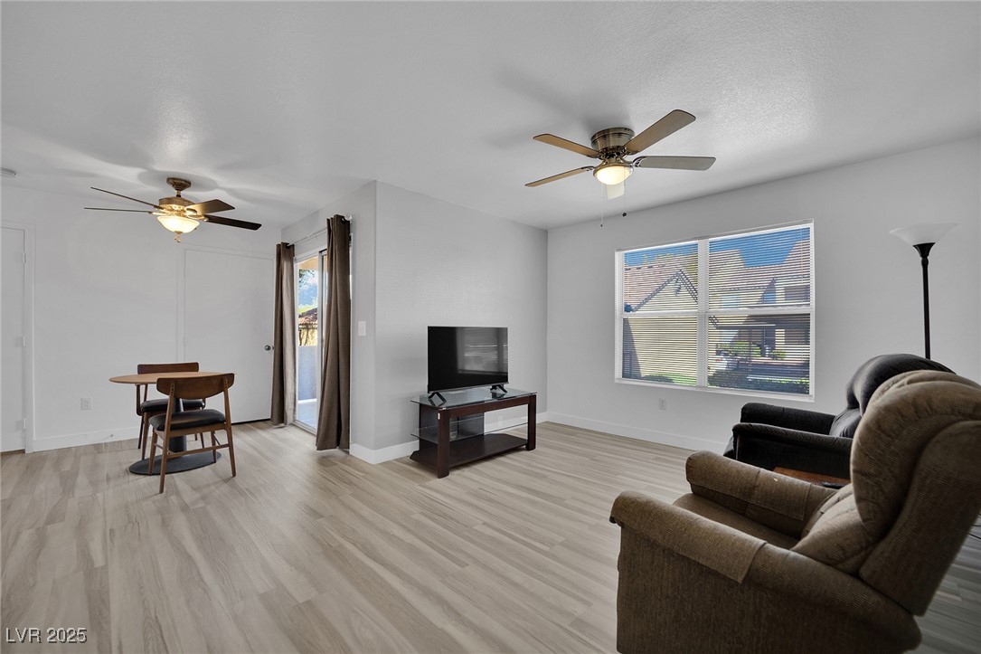 2300 East Silverado Ranch Boulevard, Unit 1189 Las Vegas, NV 89123 - Photo 8 of 27 Living room with a ceiling fan, light wood-style flooring, healthy amount of natural light, and a textured ceiling