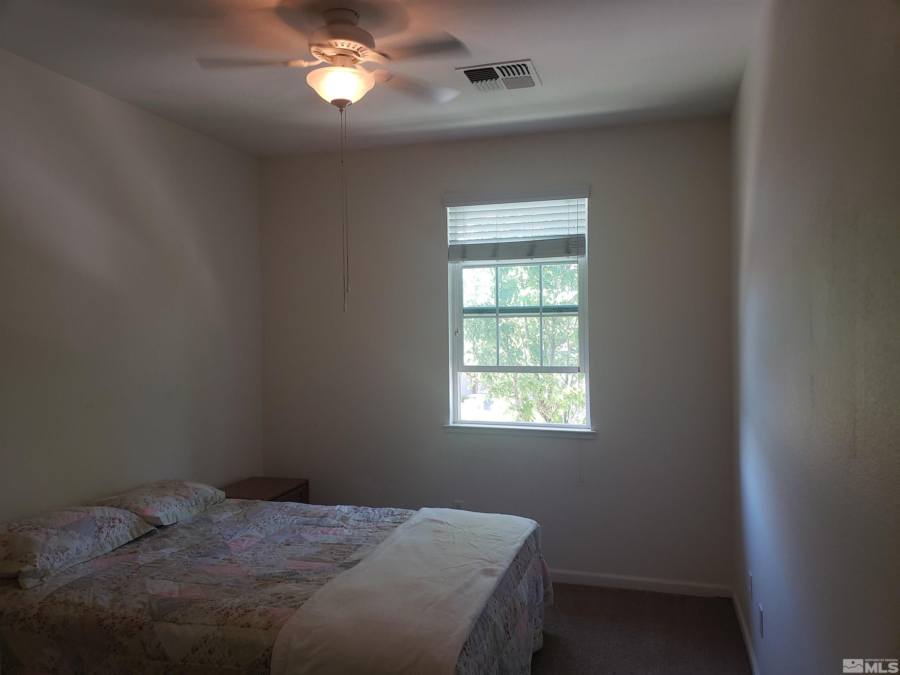1896 Wind Ranch Road, Unit A Reno, NV 89521 - Photo 28 of 36 a bedroom with a bed window and a chandelier