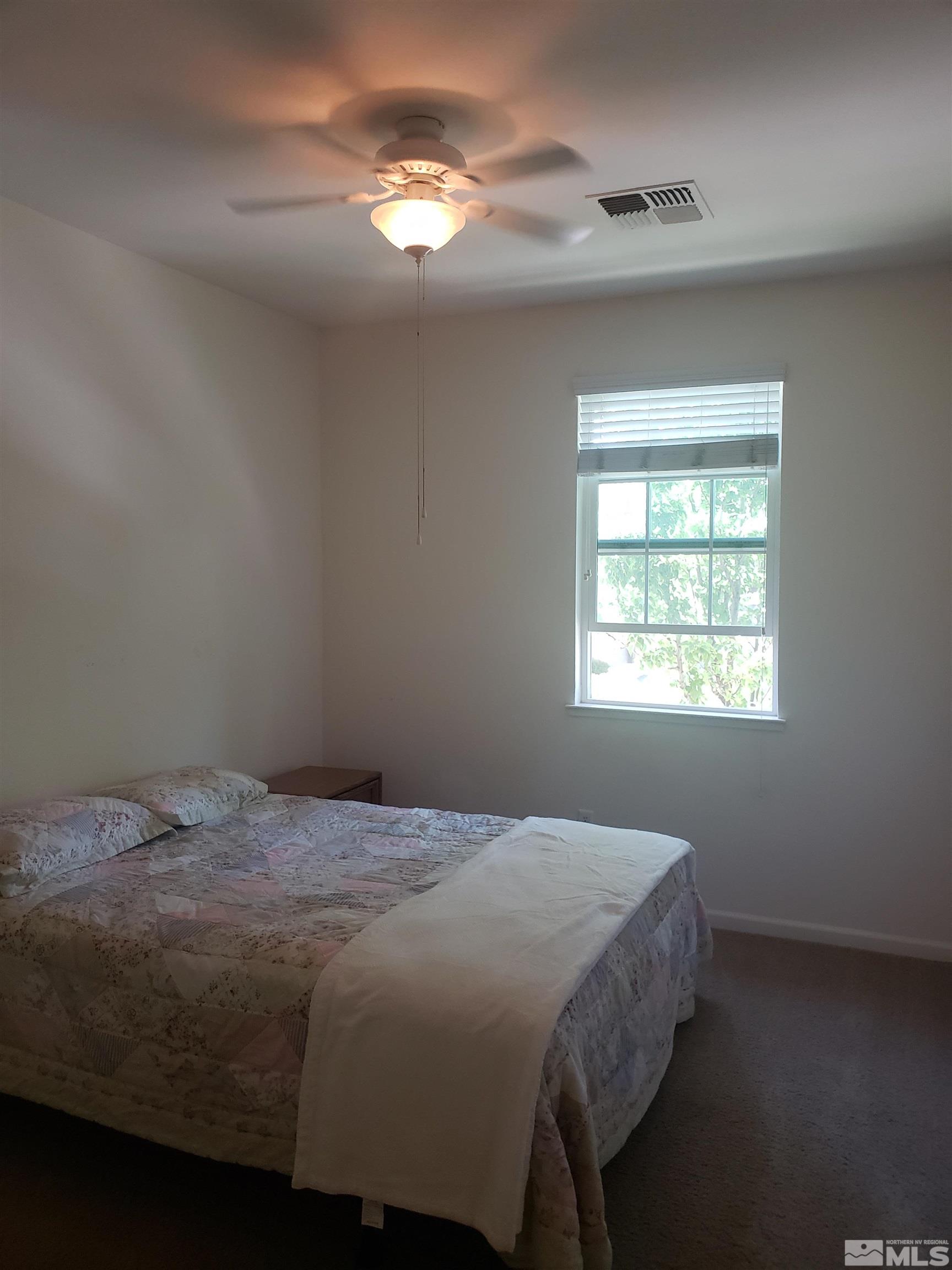 1896 Wind Ranch Road, Unit A Reno, NV 89521 - Photo 29 of 36 a bed sitting in a bedroom next to a window