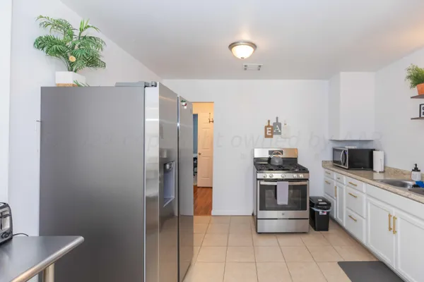 a kitchen with stainless steel appliances a stove refrigerator and a potted plant