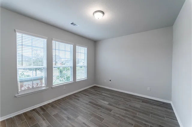 an empty room with wooden floor chandelier fan and windows