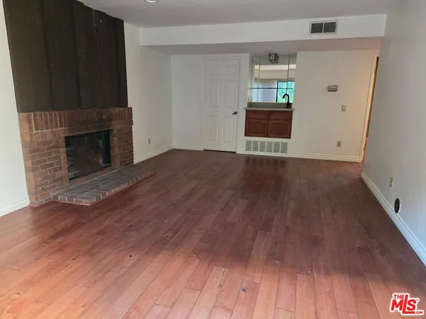 a view of a livingroom with wooden floor and a fireplace