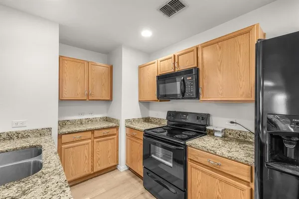 a kitchen with stainless steel appliances granite countertop a stove top oven a sink dishwasher a refrigerator and cabinets with wooden floor