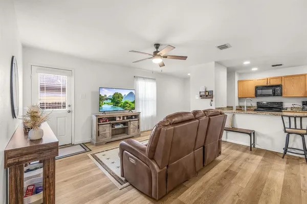 a living room with furniture and a flat screen tv with kitchen view