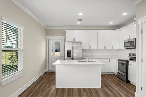 a kitchen with stainless steel appliances granite countertop a sink dishwasher a stove and a refrigerator with wooden floor