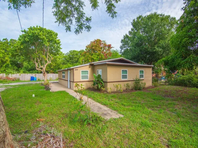 a view of a yard in front of a house with large trees