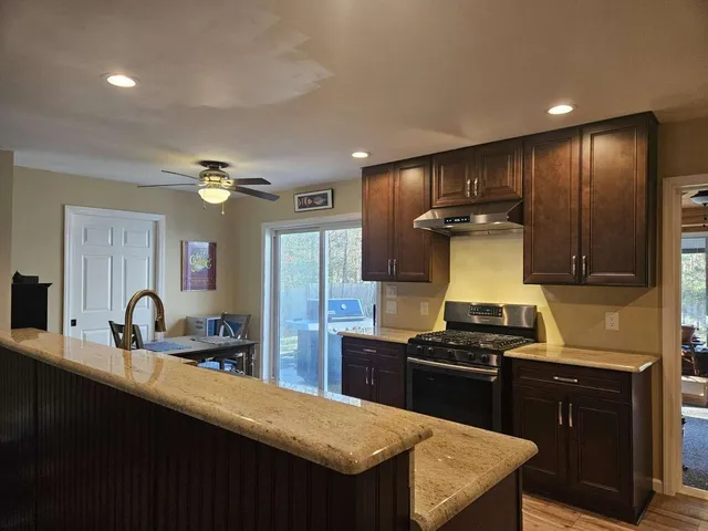 a kitchen with kitchen island granite countertop a sink stainless steel appliances and cabinets