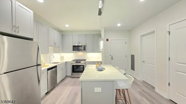 a kitchen with stainless steel appliances a refrigerator a stove a sink and white cabinets