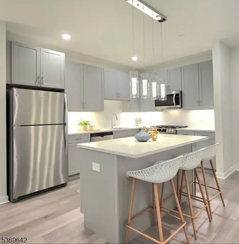 a kitchen with stainless steel appliances granite countertop a refrigerator a stove a sink dishwasher and a refrigerator with wooden floor