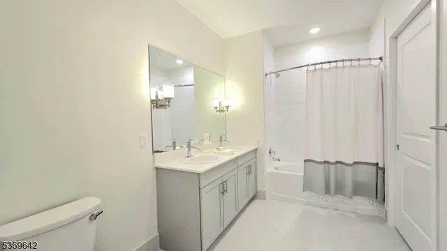 a spacious bathroom with a double vanity sink a toilet and a mirror